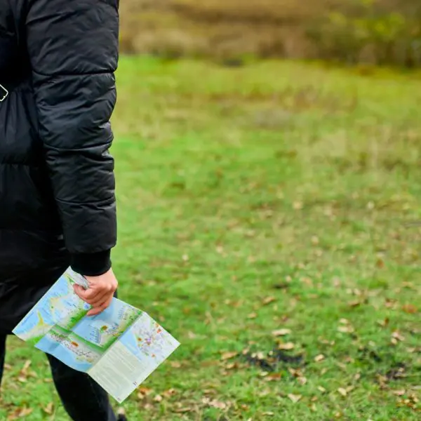 Traveller with backpack and map in hand in the wilderness