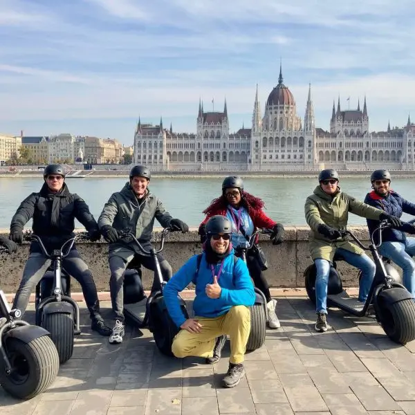 People on an e-scooter tour posing with the Parliament in the background.