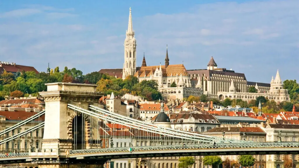 View of Buda Castle, Matthias Church, and the Chain Bridge in Budapest, Hungary, with a backdrop of a clear sky.