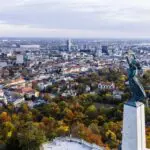 Aerial view of Budapest with the Liberty Statue atop Gellert Hill Budapest, overlooking the city, the Danube River, and colorful autumn trees.
